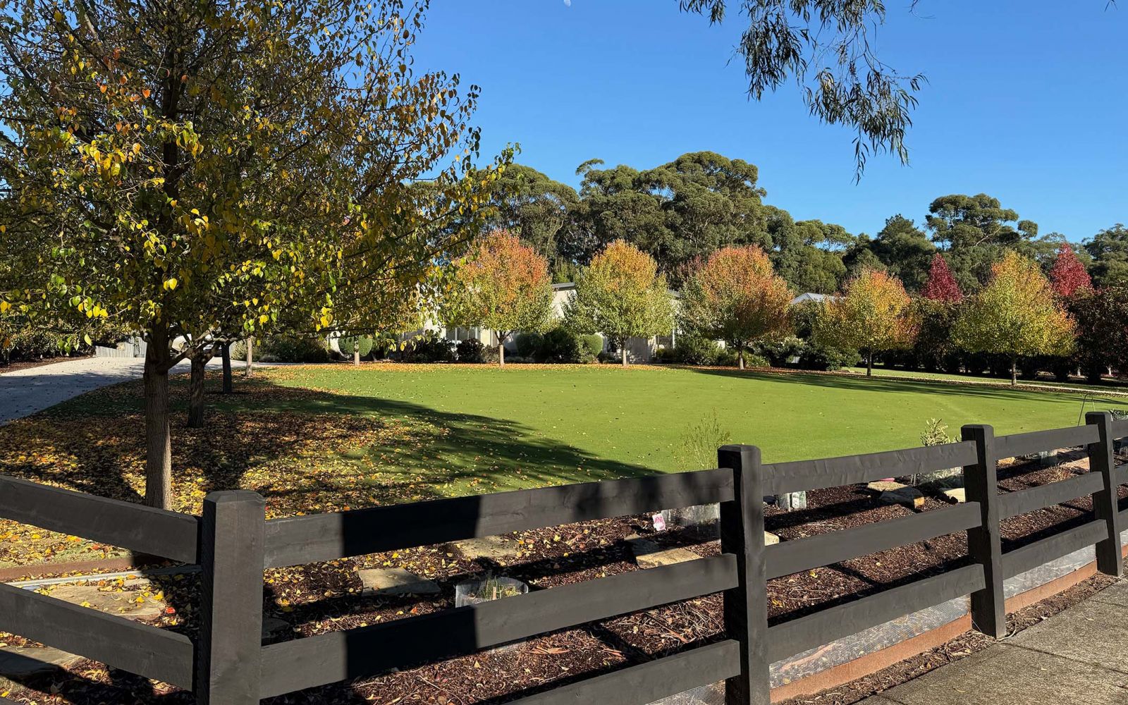 Backyard of a house features a post and rail wooden fence