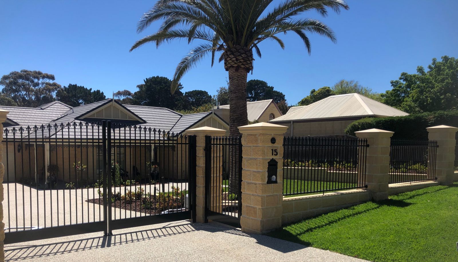 A palm tree stands in front of an aluminium fence, creating a serene and tropical atmosphere