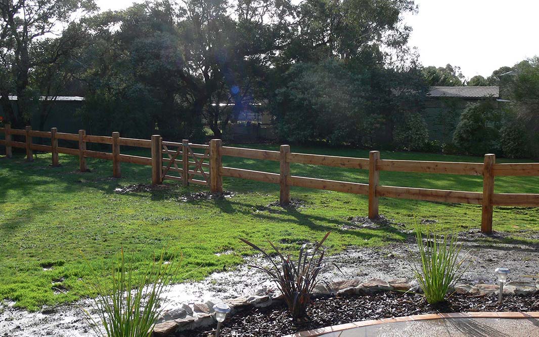 Backyard of a house features a post and rail wooden fence